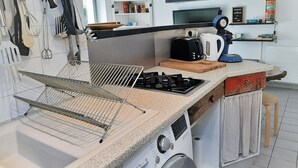 A modern kitchen with a built-in washer, a gas stove, and various kitchen utensils. - Cozy 4-Person Apartment Steps from Beach, BBQ, WiFi & Parking (Capbreton)