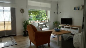 A modern living room with a sofa, TV, and potted plants.