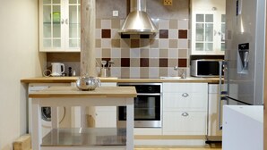 A compact kitchen with a built-in oven, a microwave, and a stainless steel refrigerator.