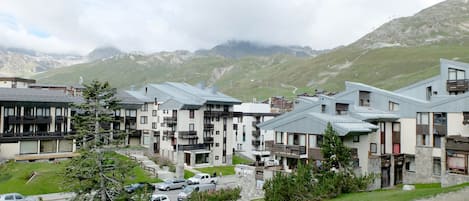 A row of modern buildings with a stone facade, set against a mountainous backdrop.