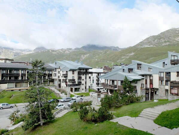 A row of modern buildings with a stone facade, set against a mountainous backdrop.