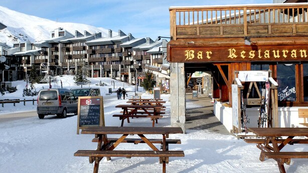 A bar restaurant with outdoor seating and a snowy mountain backdrop.