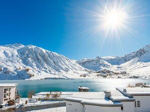 Een berglandschap met sneeuw, een meer en gebouwen op de voorgrond.