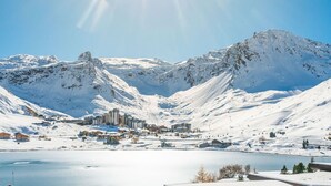 Un paysage de montagne enneigé, avec une ville au premier plan et un lac.