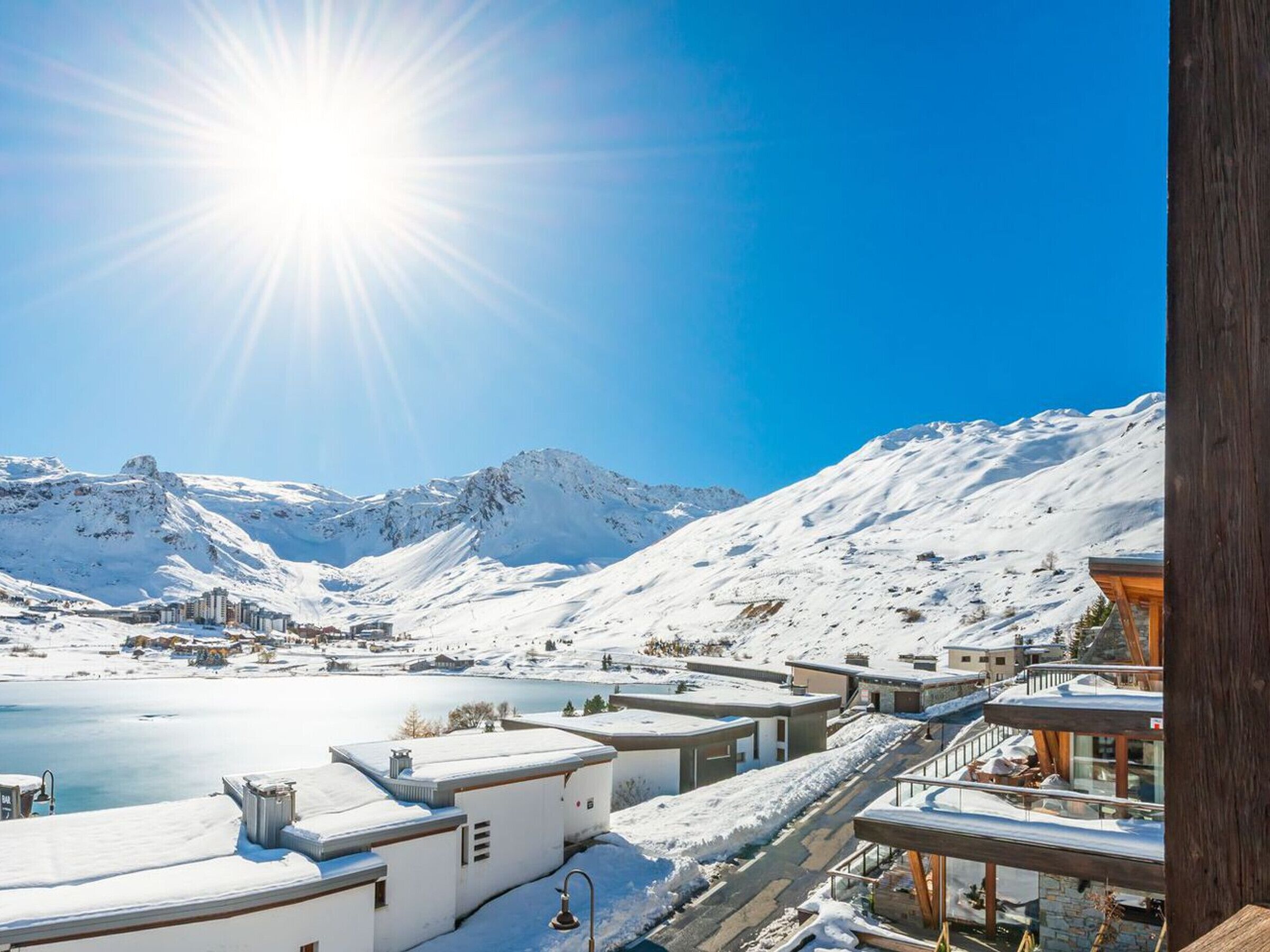 A snow-covered mountain landscape with a clear sky and a bright sun.