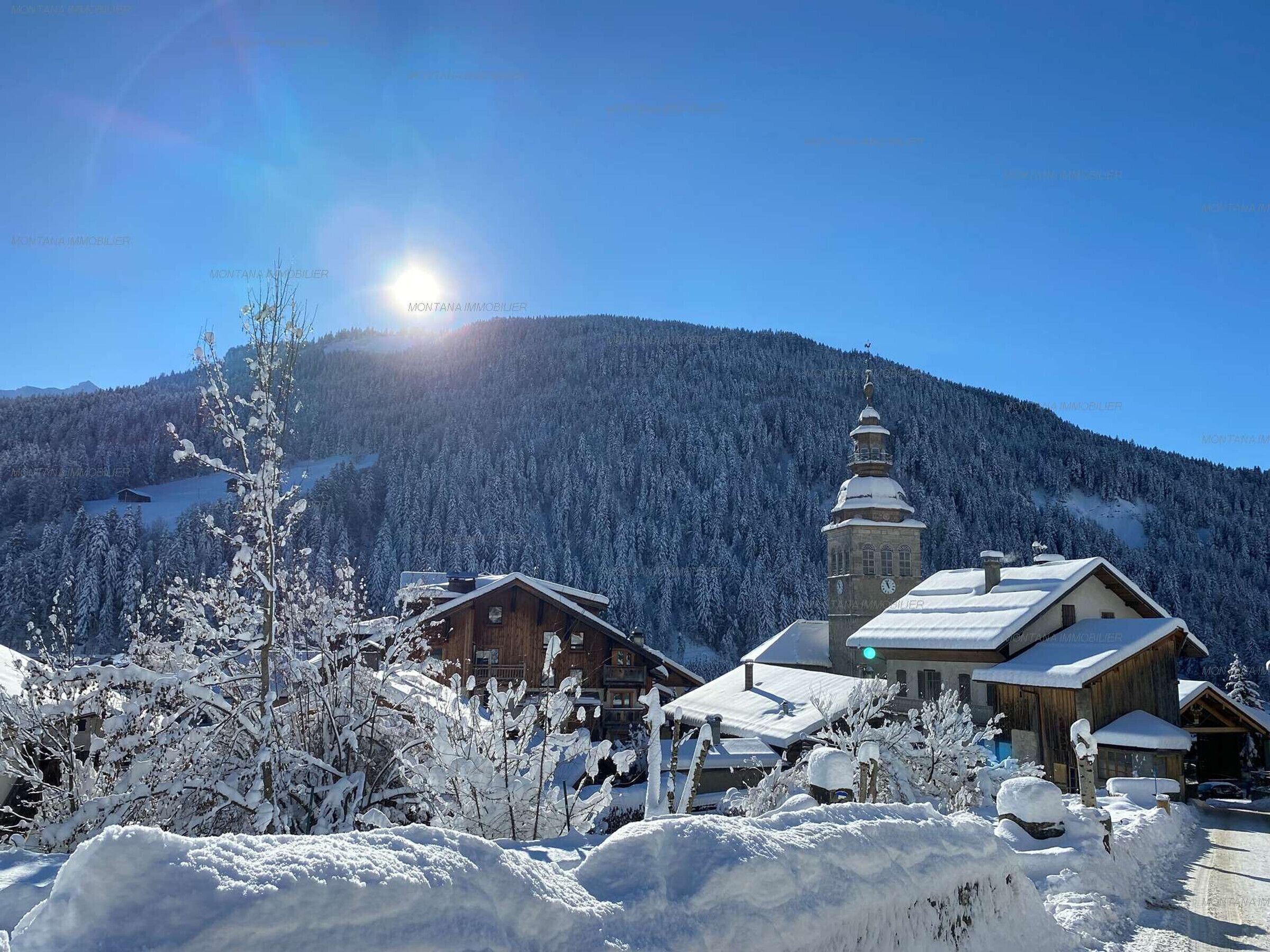 A snow-covered mountain village with wooden buildings and a church.