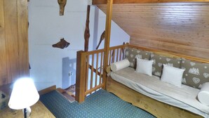 A cozy room with a wooden ceiling, a bunk bed with a mattress and pillows, a lamp, and wall-mounted wooden decorations.