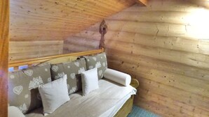 A cozy wooden cabin room with a bed, pillows, and a sloped ceiling.