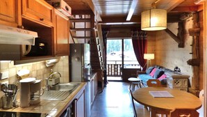 A kitchen with wooden cabinets, a refrigerator, a sink, and a coffee maker. There is a dining area with a table and chairs.