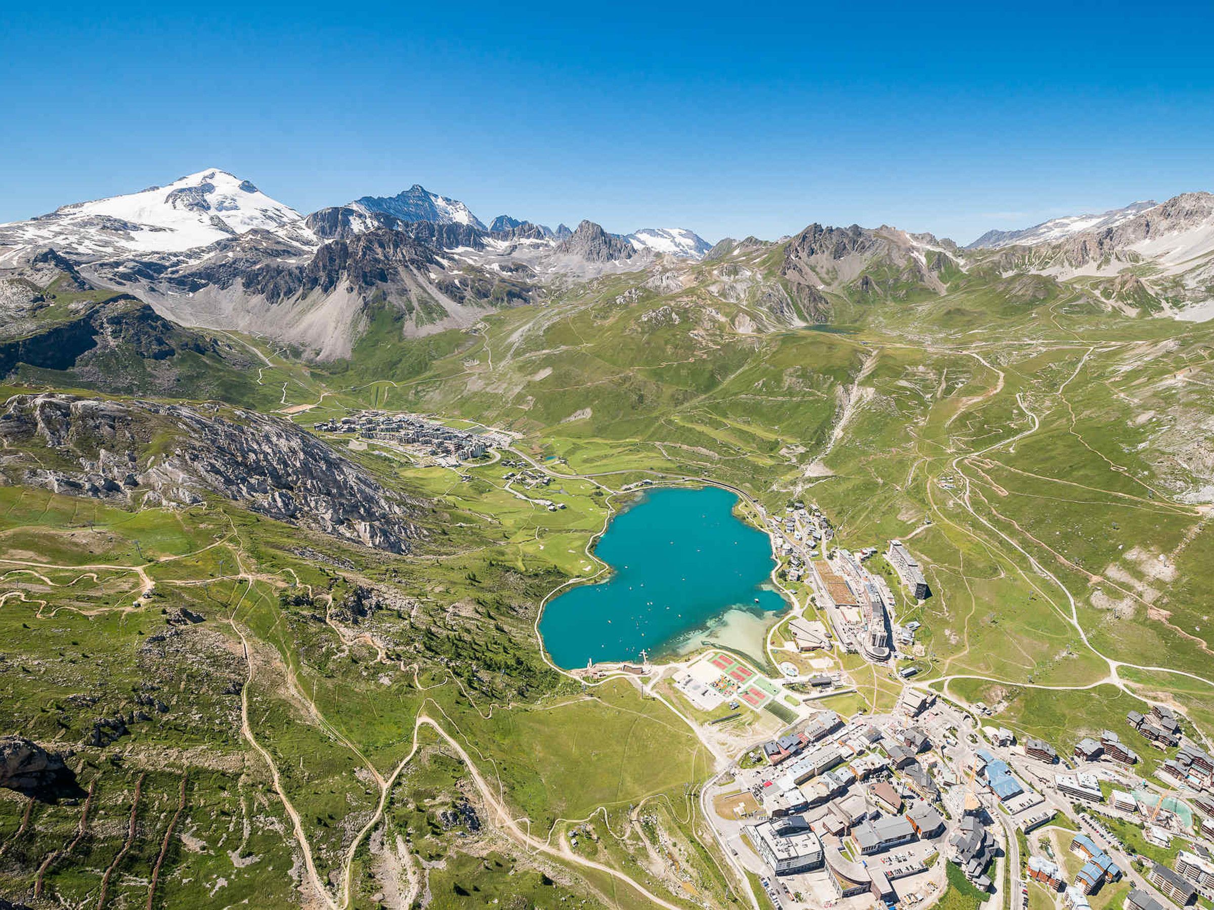 Une vue aérienne d’une région montagneuse avec un lac, des routes et un ensemble de bâtiments.