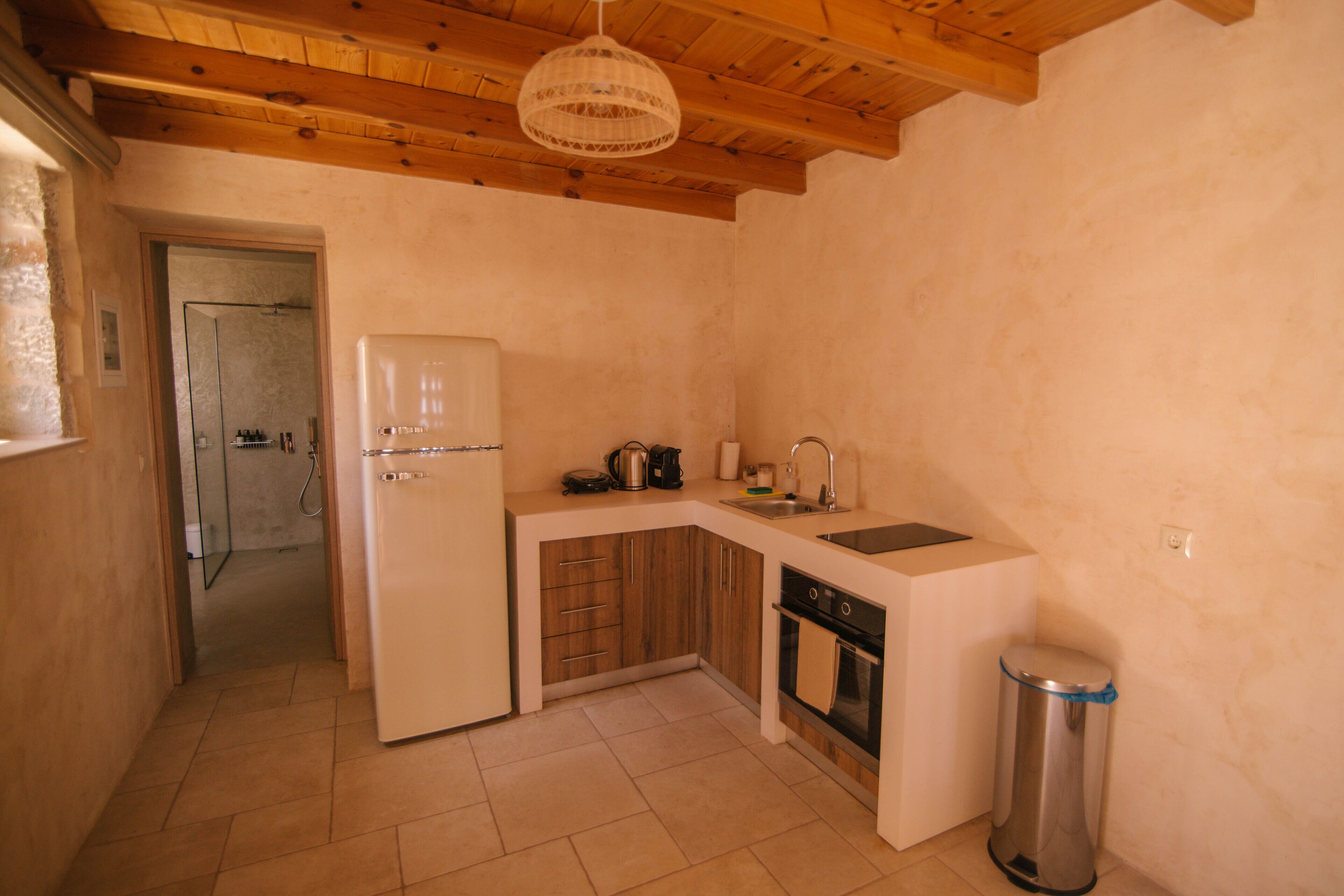 A compact kitchen with a refrigerator, stove, sink, and wooden cabinets.