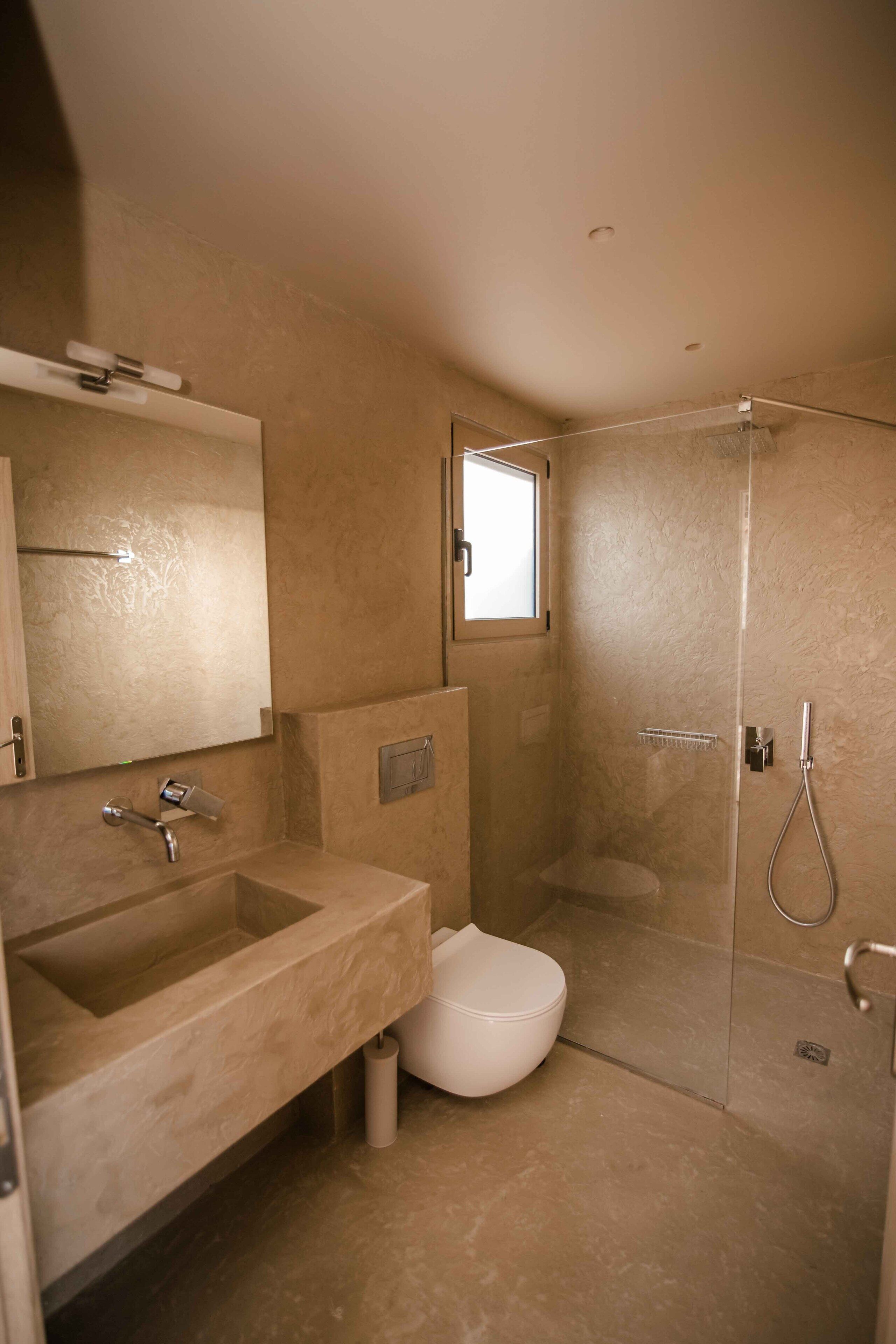 Une salle de bain équipée d’un lavabo, d’un miroir, de toilettes et d’une douche à parois en verre.