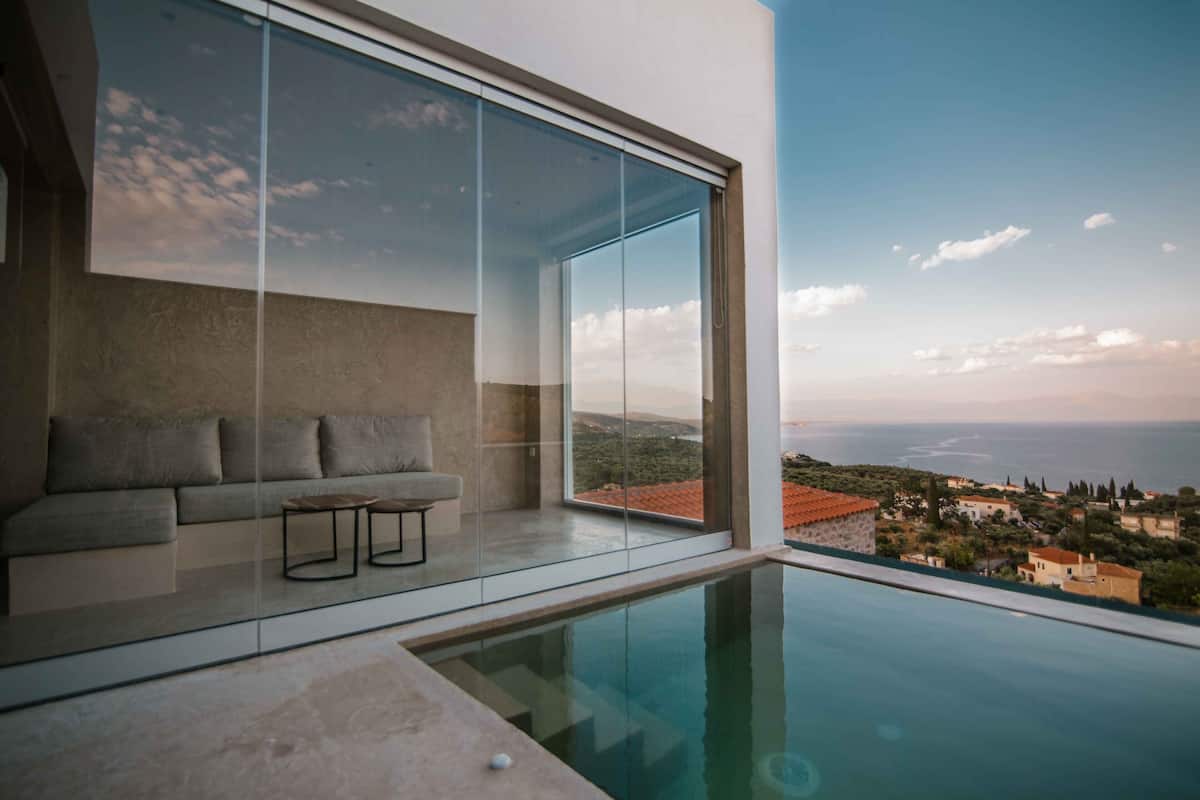 Un salon moderne avec un mur en verre, une piscine et une vue sur la mer.