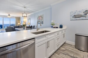 Una cocina moderna con armarios blancos, lavavajillas de acero inoxidable y una isla grande con pileta.
