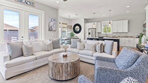 A spacious living room with a large L-shaped sofa, a round coffee table, and patterned armchairs. - Dancing Heron - West End PCB, Pool + Golf Cart 🛺, Sleeps 12 (Panama City Beach)