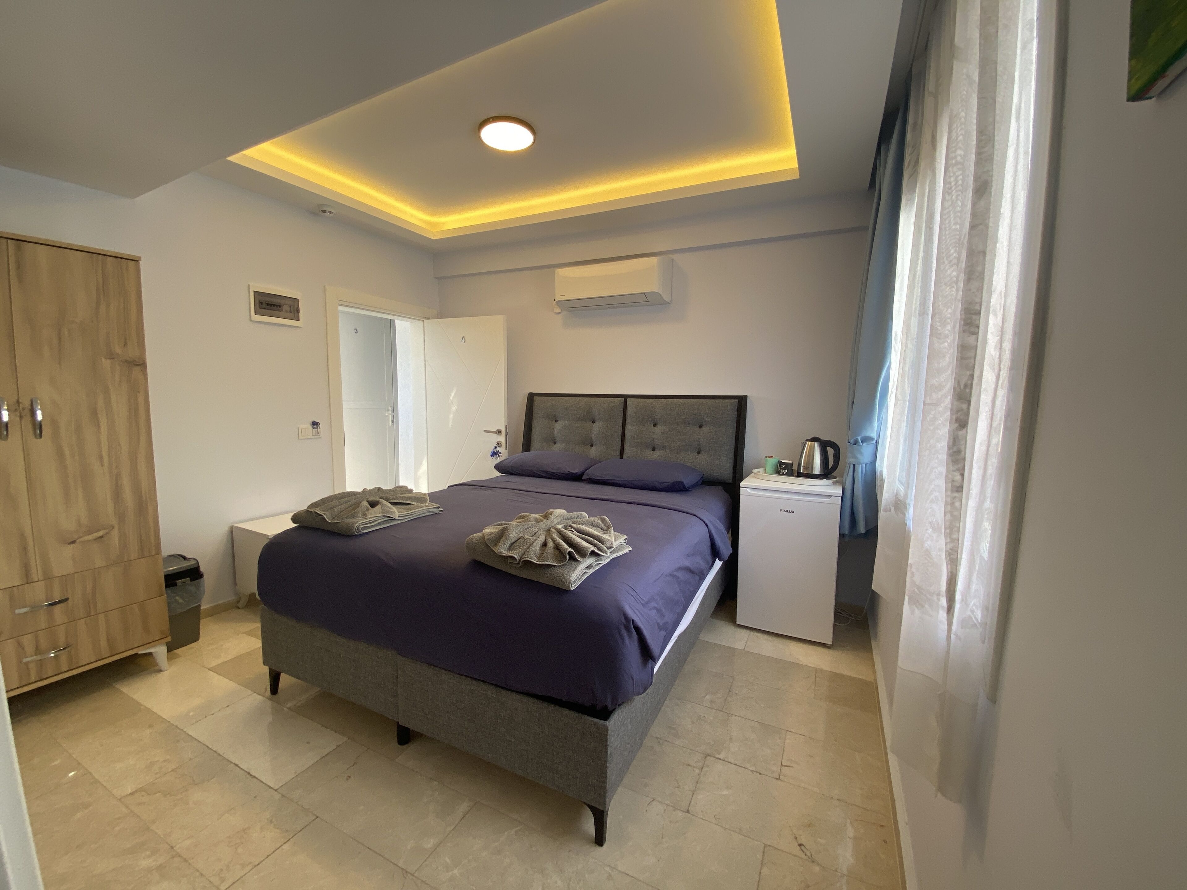 A modern bedroom with a bed, bedside table, and a small white appliance.