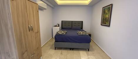 A bedroom with a bed, wardrobe, bedside table, and a painting on the wall.