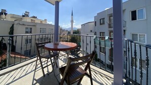 Un balcón con mesa y sillas, con vistas a una zona residencial con edificios y una mezquita.