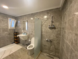 Eenvoudige vierpersoonskamer | Badkamer | Een douche, een regendouche, een haardroger, handdoeken