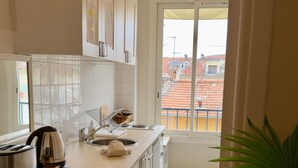 A kitchen with white cabinets, a countertop, a sink, and a window with a view of buildings. - URBAN AP4346 By Riviera Holiday Homes (Niza)