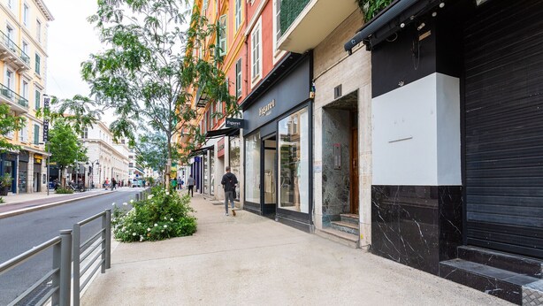 A sidewalk next to a building with a closed shutter, a sign for 'Figaret', and a pedestrian walkway. - URBAN AP4346 By Riviera Holiday Homes (Niza)