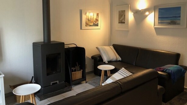 Un salon chaleureux avec un canapé, une petite table, une cheminée et des œuvres d’art accrochées au mur.