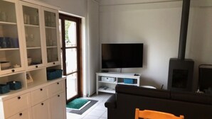 Un salon équipé d’un téléviseur, d’un canapé et d’un coin repas avec une table et des chaises.