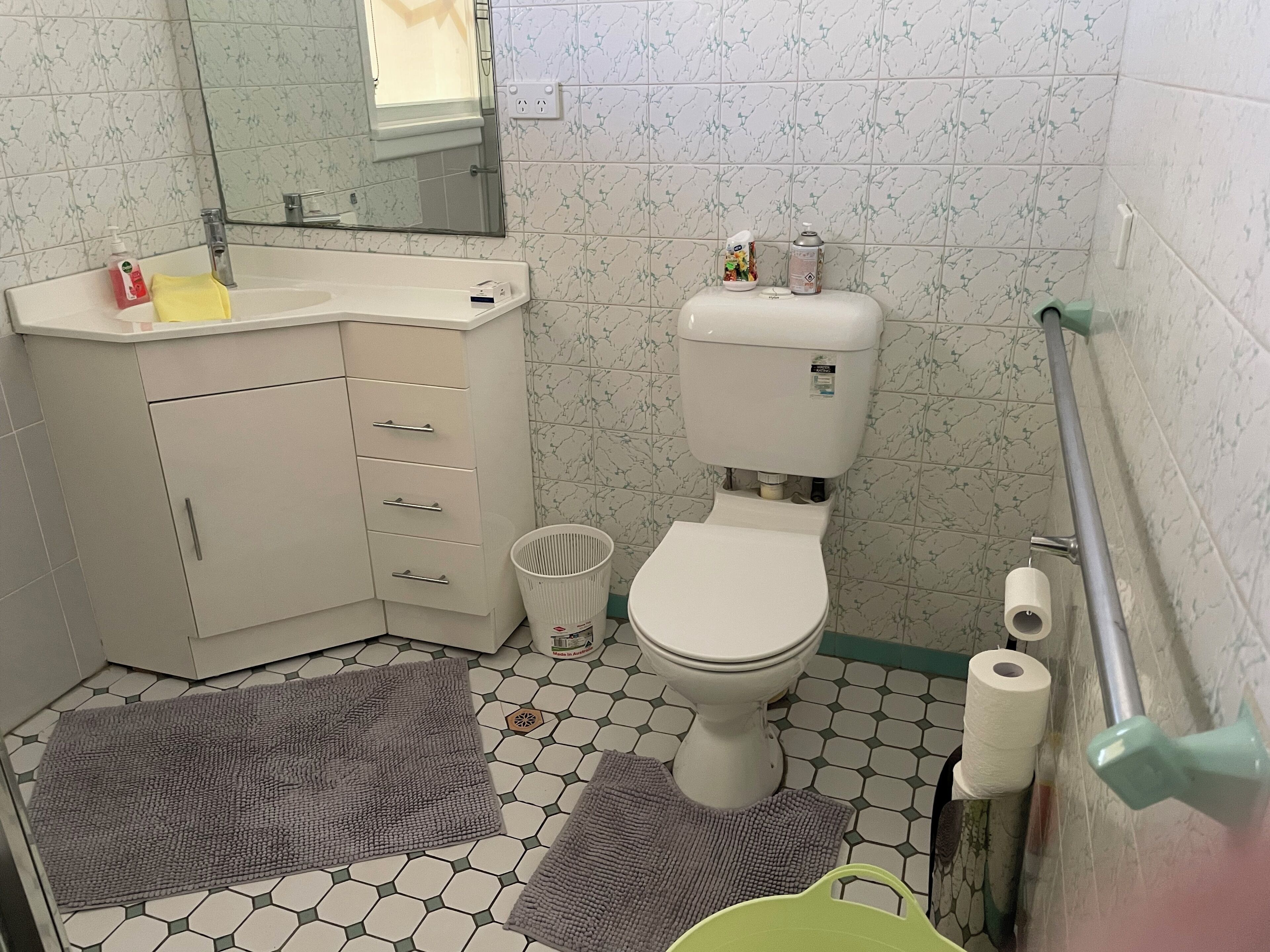 A bathroom with a toilet, sink, and mirror.