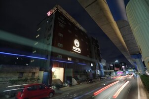 Et hotel med et tydeligt skilt, en trappe, der fører til indgangen, og en travl gade med trafik.