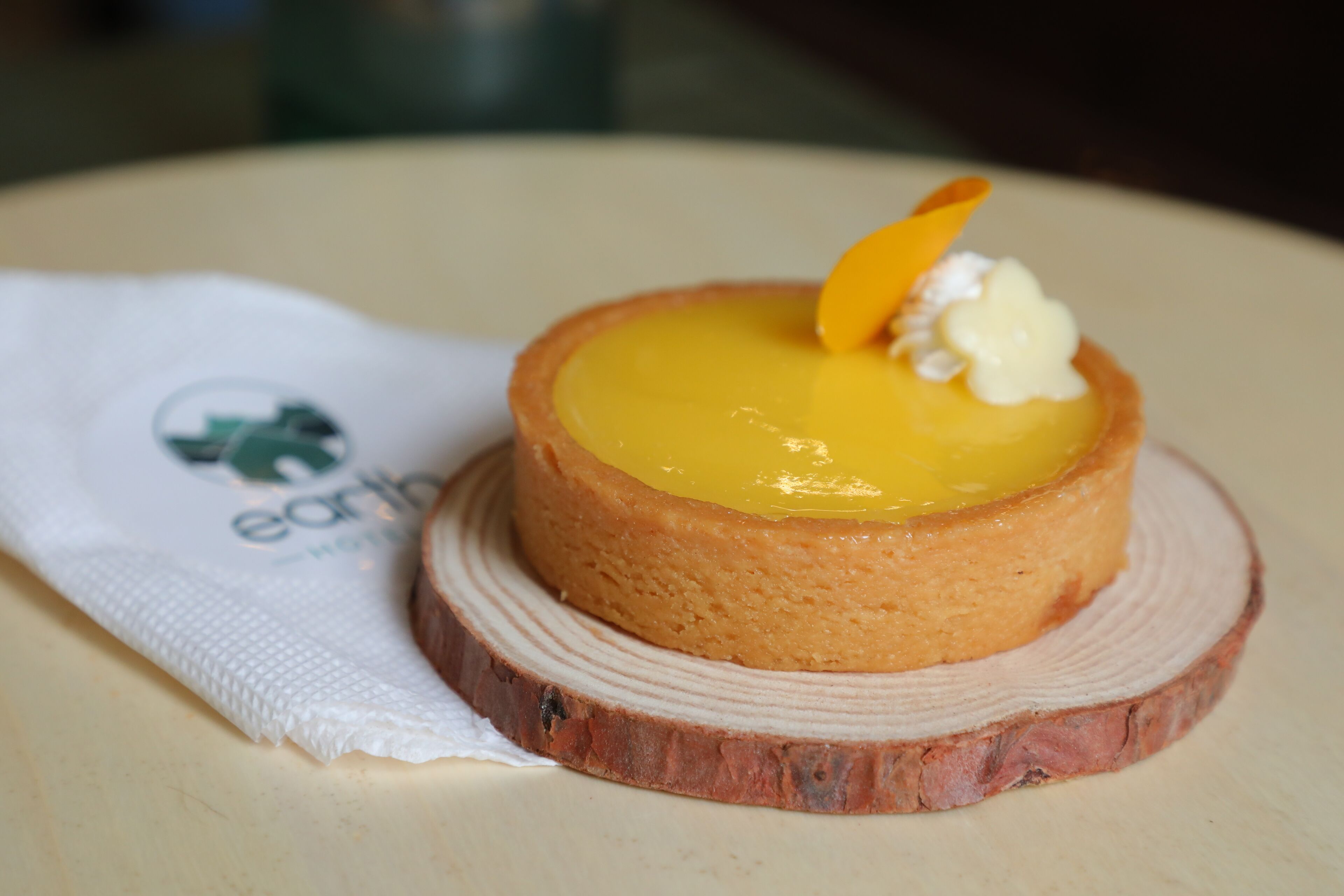 Un postre redondo sobre un plato de madera con un paño blanco a un lado.