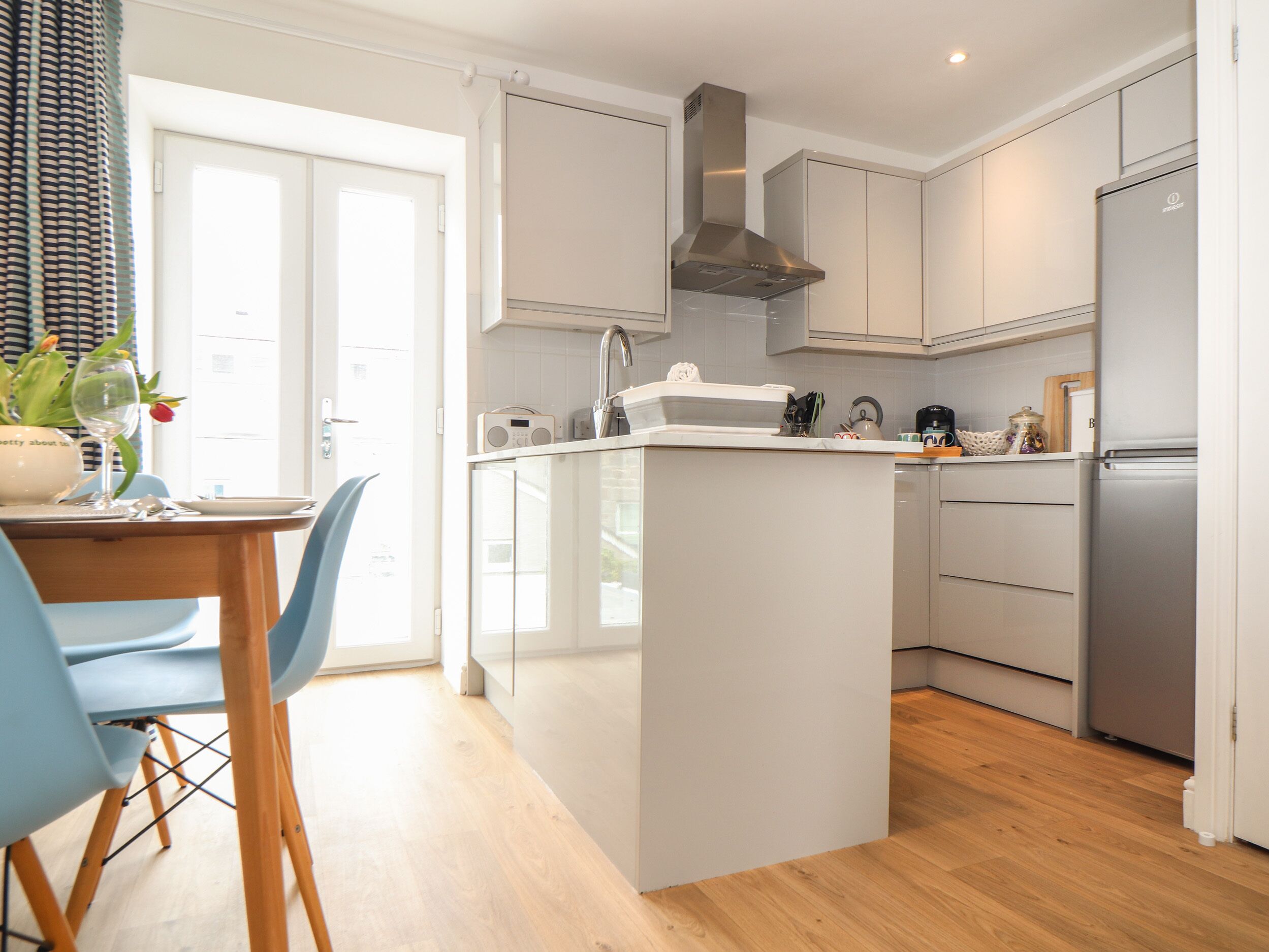 A modern kitchen with white cabinetry, a central island, and a built-in oven.