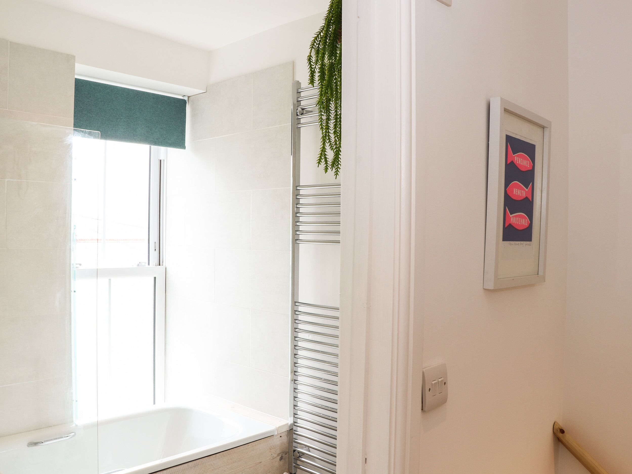 Ein modernes Badezimmer mit einer Badewanne, einem Handtuchhalter und einem gerahmten Kunstwerk an der Wand.