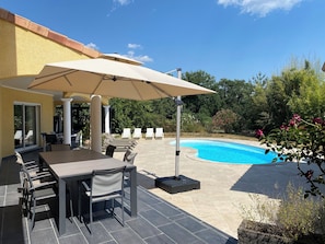 A patio area with a pool, outdoor seating, and a covered table.
