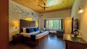 A modern hotel room with a large bed, a desk, a chair, and a view of the forest through the window. - Olive County Manali (Manali)