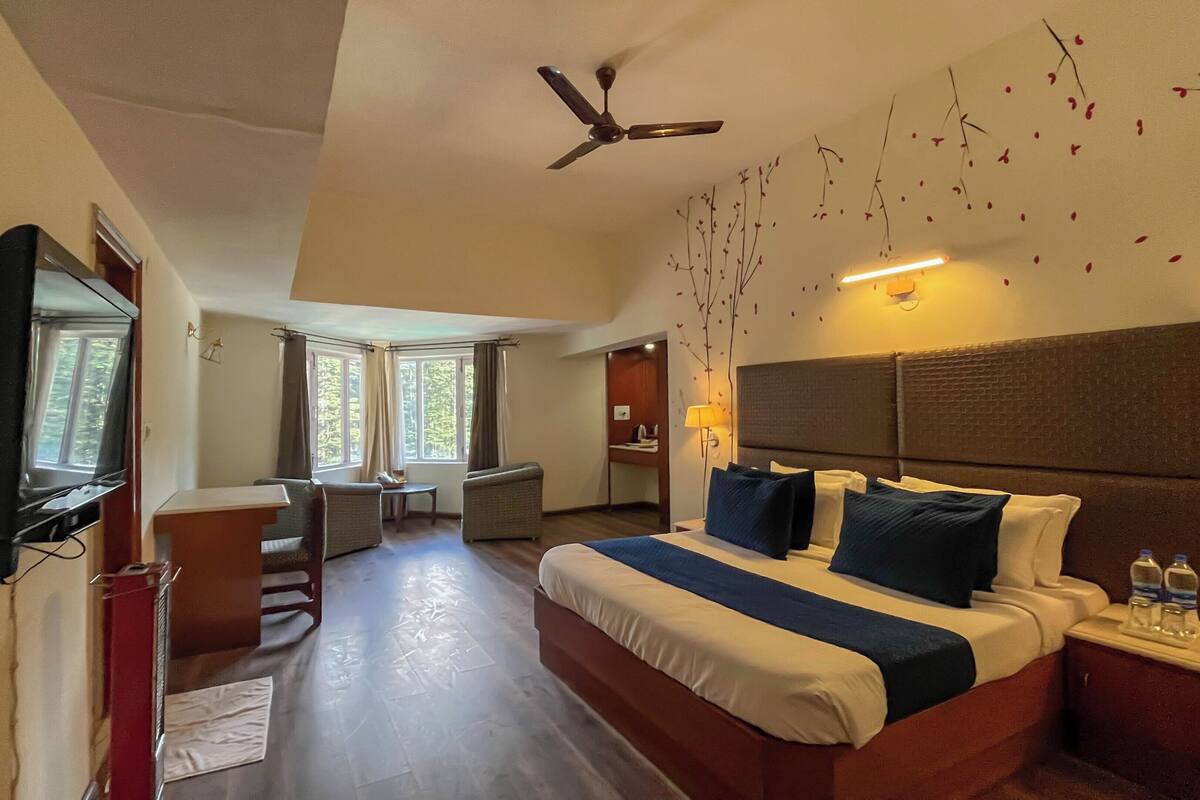 A hotel room with a large bed, a desk, a chair, and a TV.