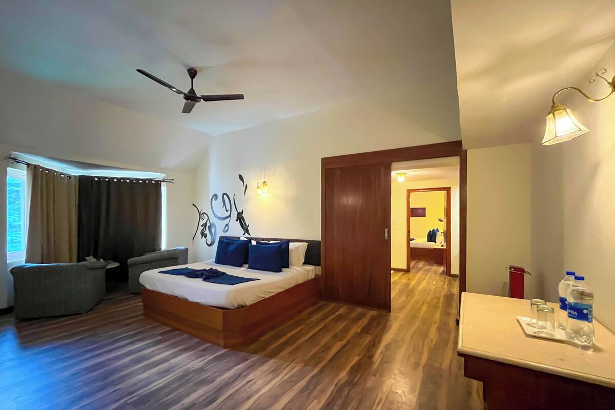 A hotel room with a bed, a desk, a chair, a ceiling fan, and a window with curtains.
