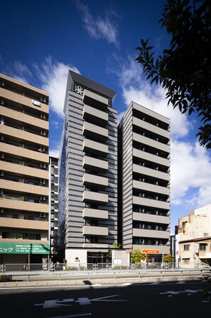 A modern hotel with multiple floors, a prominent entrance, and a clear view of the sky. - R Hotel Namba South (Osaka)