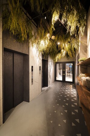 A hallway with a patterned floor, elevator doors, and a ceiling with hanging greenery.
