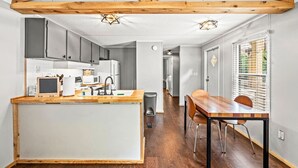 Eine moderne Küche mit Holzbalken, einer zentralen Kochinsel und einem Essbereich mit Tisch und Stühlen.