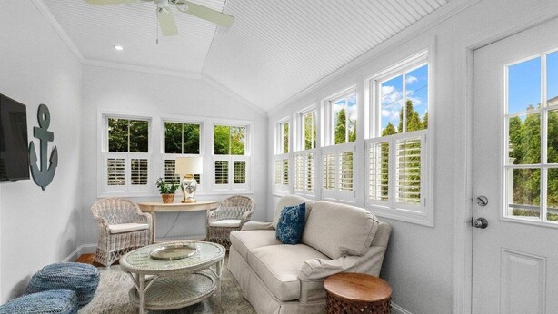 A sunlit room with white walls, a ceiling fan, wicker furniture, and a large window with shutters. - Stroll Chatham's Historic Downtown / Shops, Dining, Galleries, Etc. (Chatham)