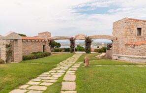 A stone pathway leading to a stone archway with a view of the sea. - Villetta Ashlar - SARDINIA UNLIMITED (Porto Cervo)