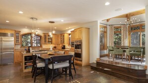Una cocina amplia con armarios de madera, una isla central y un comedor con sillas.