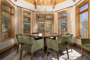 A dining area with a round table, six chairs, and large windows with curtains. - Short walk to downtown, shuttle, hot tub, game room, walk to two parks! (Breckenridge)