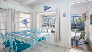 A room with a glass table and chairs, white walls, and a view of the marina. - Captain's Quarters 3bed/2bath mobile home with dockage (Marathon)