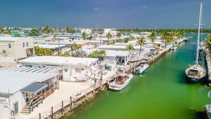 A marina with boats docked, a clear sky, and buildings along the waterfront. - Captain's Quarters 3bed/2bath mobile home with dockage (Marathon)