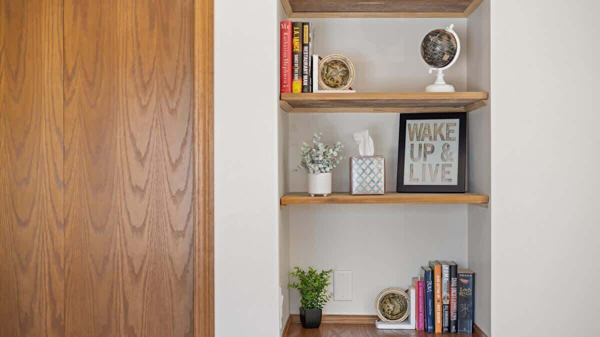 A wooden bookshelf with books, decorative items, and a framed motivational quote.