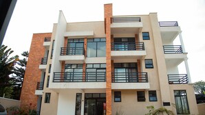 A multi-story residential building with balconies, large windows, and a brick facade. -  JLD Apartments (Kigali)