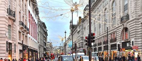 A busy urban street with pedestrians, vehicles, and ornate buildings.