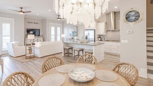 A modern kitchen with white cabinetry, a central island, and a dining area with wicker chairs and a wooden table.