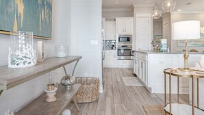 A modern kitchen with white cabinetry, stainless steel appliances, and a wooden floor.